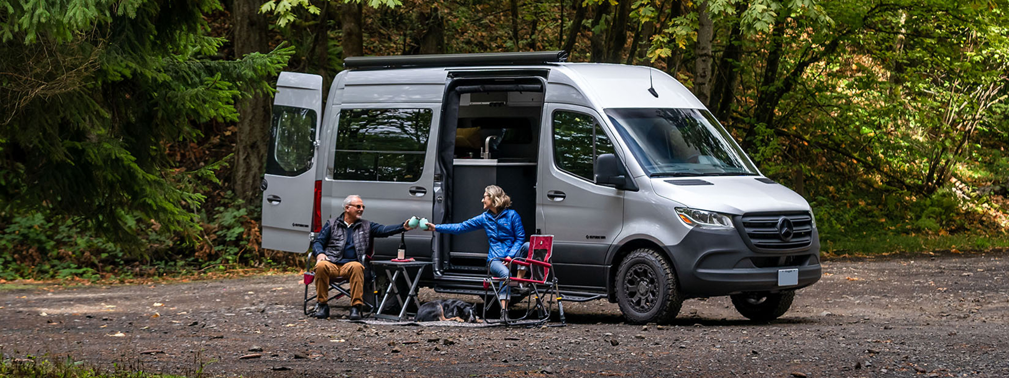 Happy couple raise their glasses together while outside their custom van