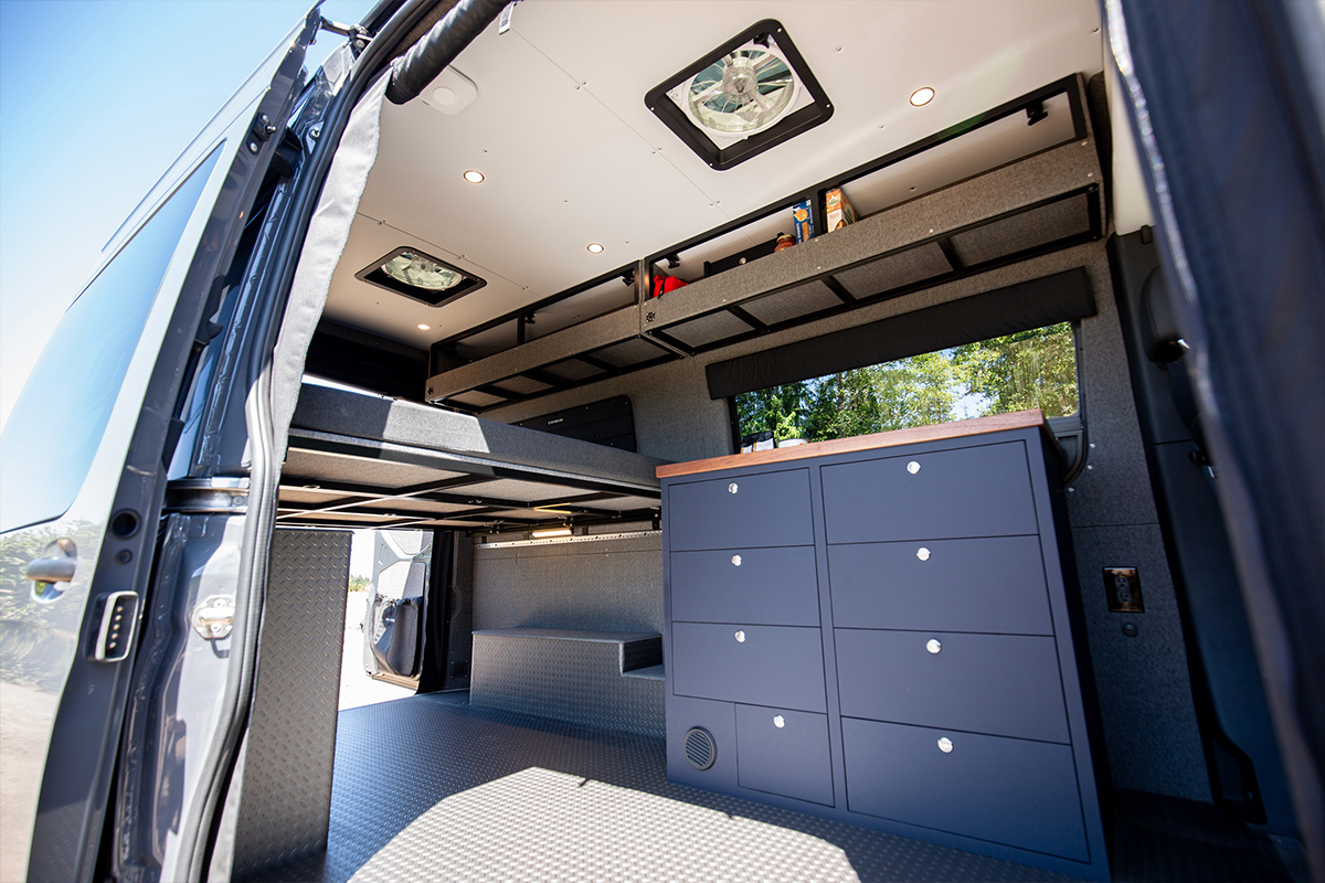 Wide interior image of converted 144 sprinter van with blue cabinetry and white ceiling