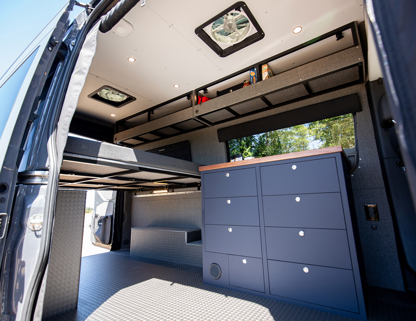 Wide interior image of converted 144 sprinter van with blue cabinetry and white ceiling