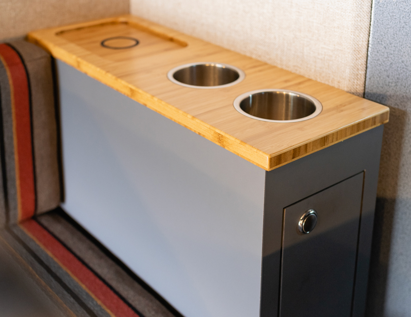 Thin storage box with bamboo and metal designated cup holders next to custom upholstered seat